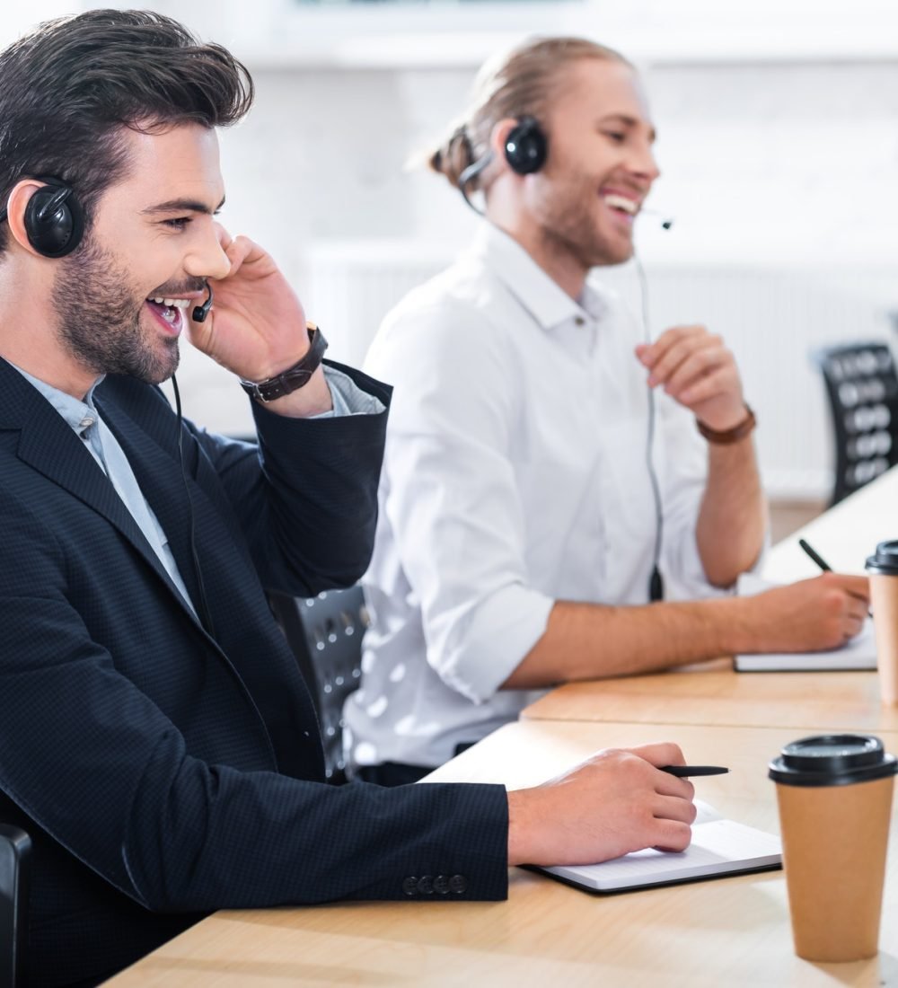 side-view-of-male-call-center-operators-in-headsets-at-workplace-in-office.jpg